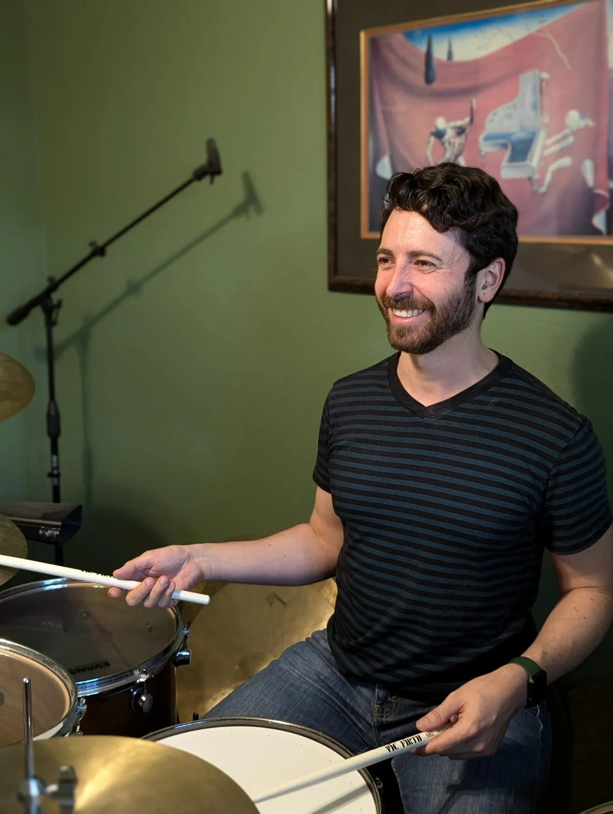 Dr. Rigel Smart smiling while playing a drum kit and holding drumsticks
